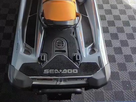 Traseira de um Sea-Doo GTi 130 com o tapete preto novo, sobre piso quadriculado na oficina